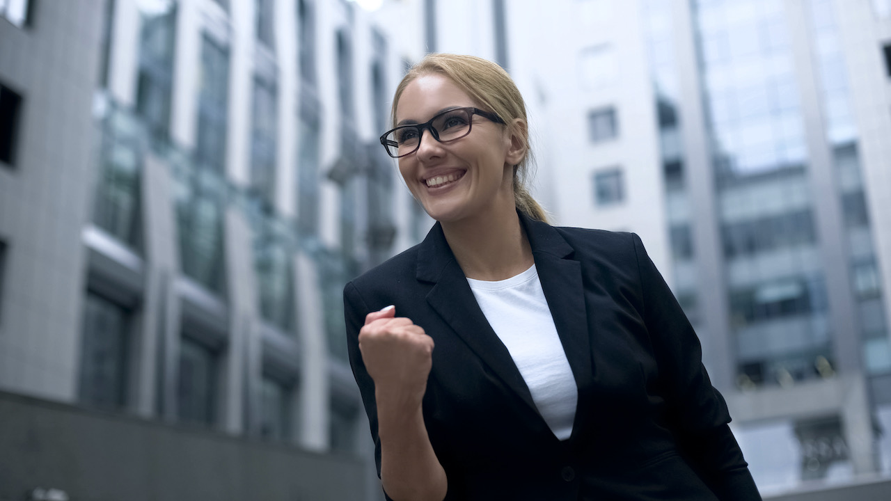 business-woman-showing-yes-gesture--rejoices-at-promotion-and-successful-career